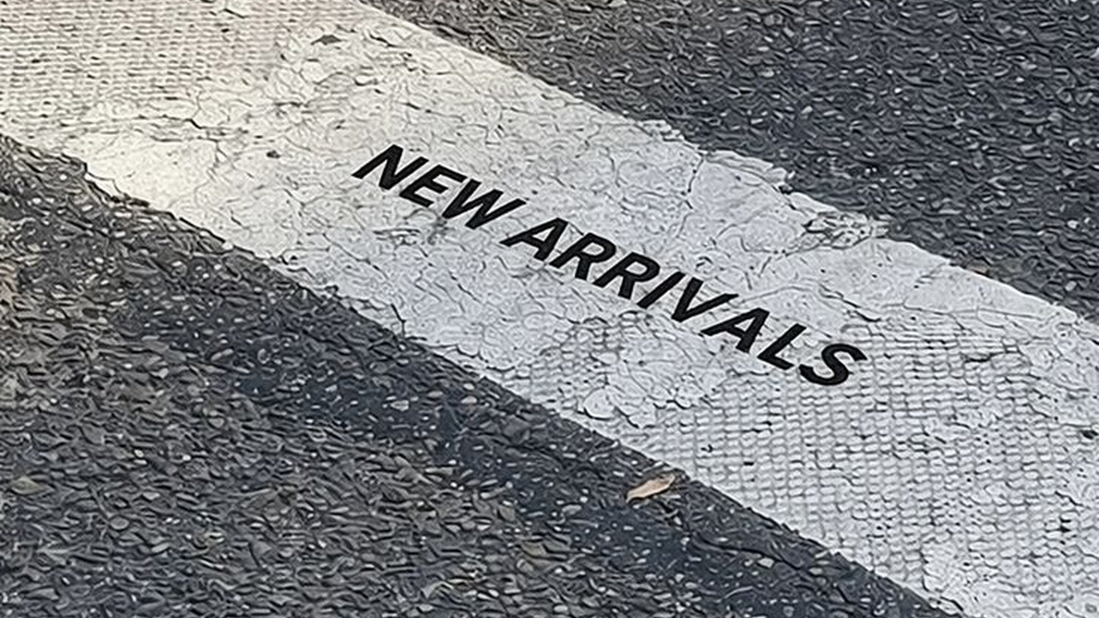 The words "New Arrivals" painted in white lettering on dark pavement.