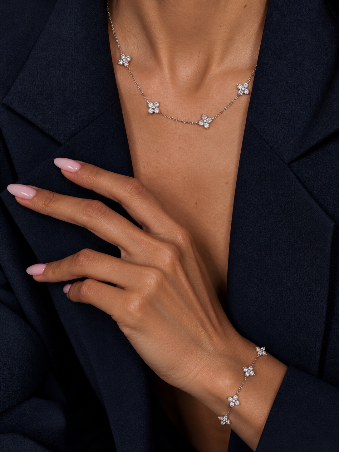 Silver-tone Fiore BRACELET and Fiore NECKLACE with clear stone flowers, worn with a navy blazer.