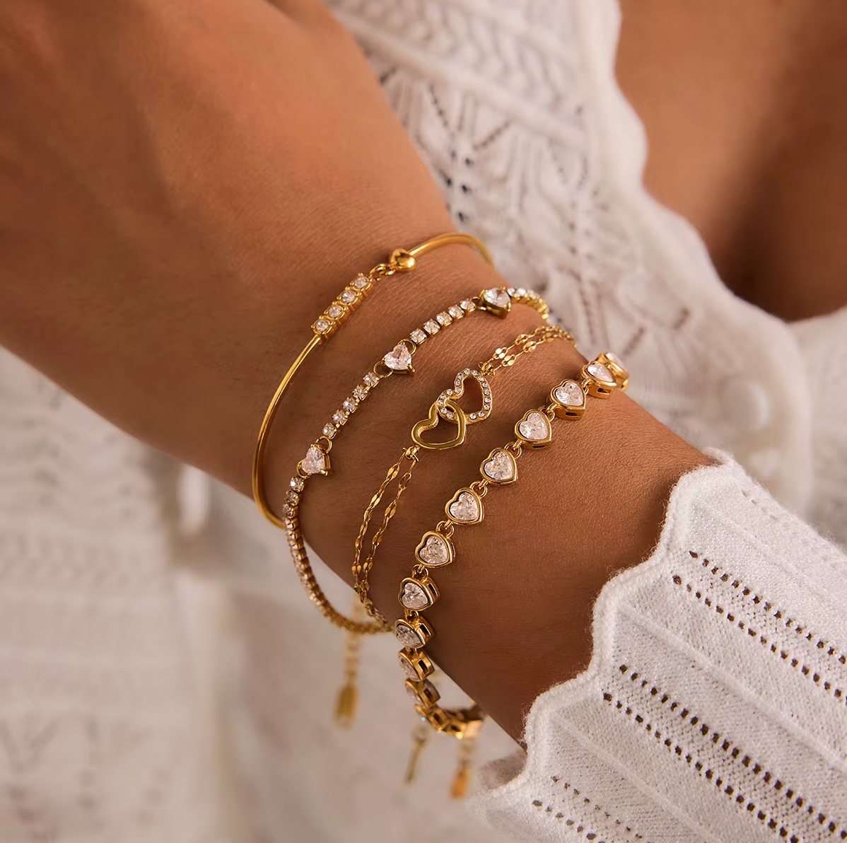 Gold-plated double-chain bracelet with two intertwined heart charms, one polished and one set with clear crystal stones