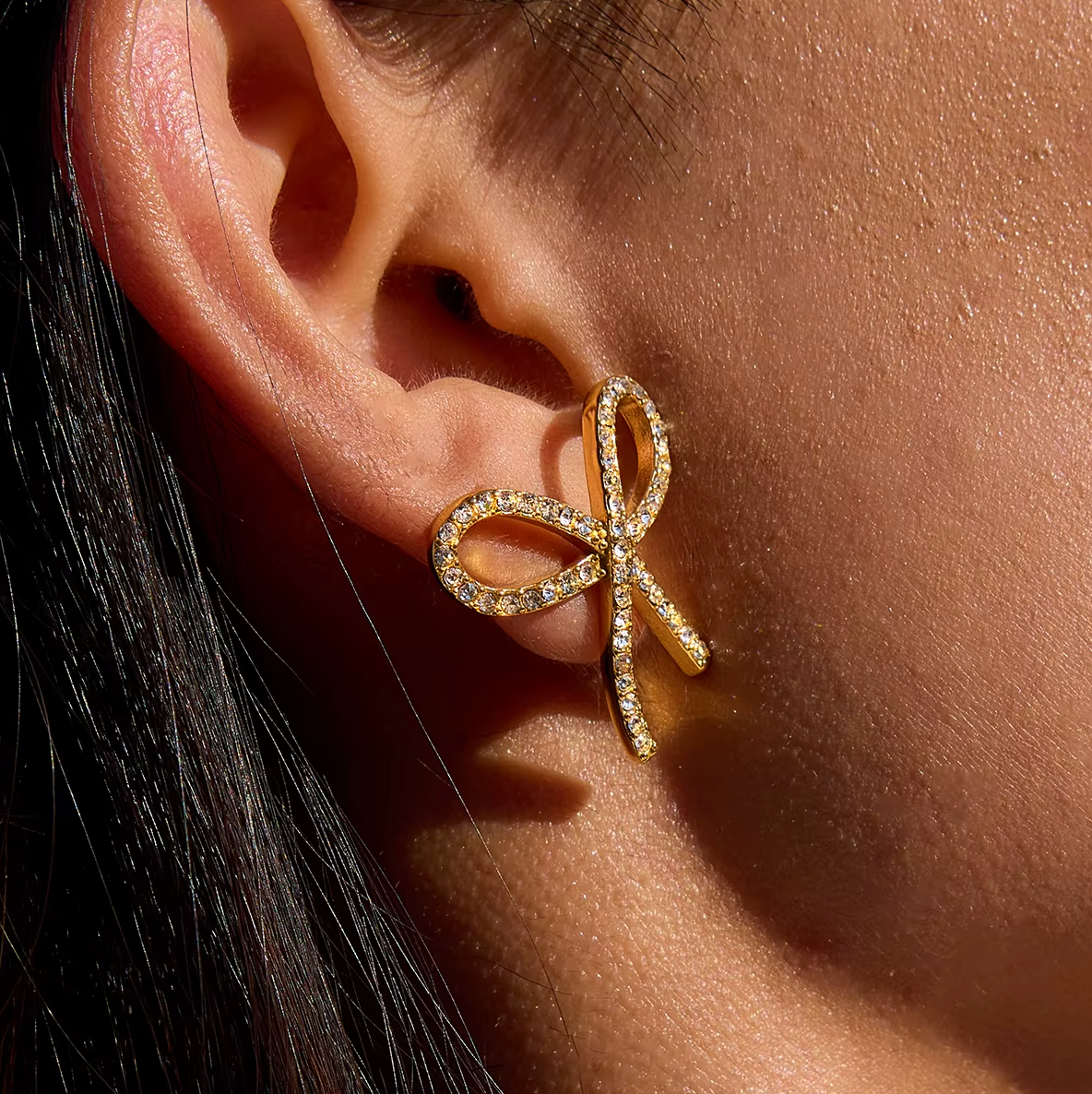 Gold-plated bow-shaped stud earrings embellished with clear crystal stones