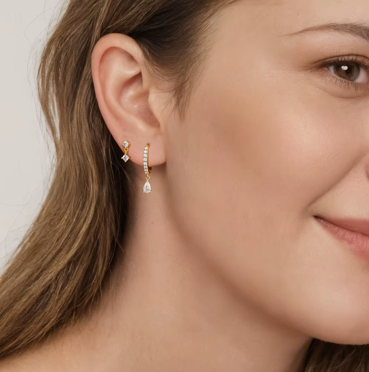 Two matching earring sets displayed on a white background, featuring gold and silver stud and huggie earrings with clear crystal stones and delicate drop charms, arranged vertically.