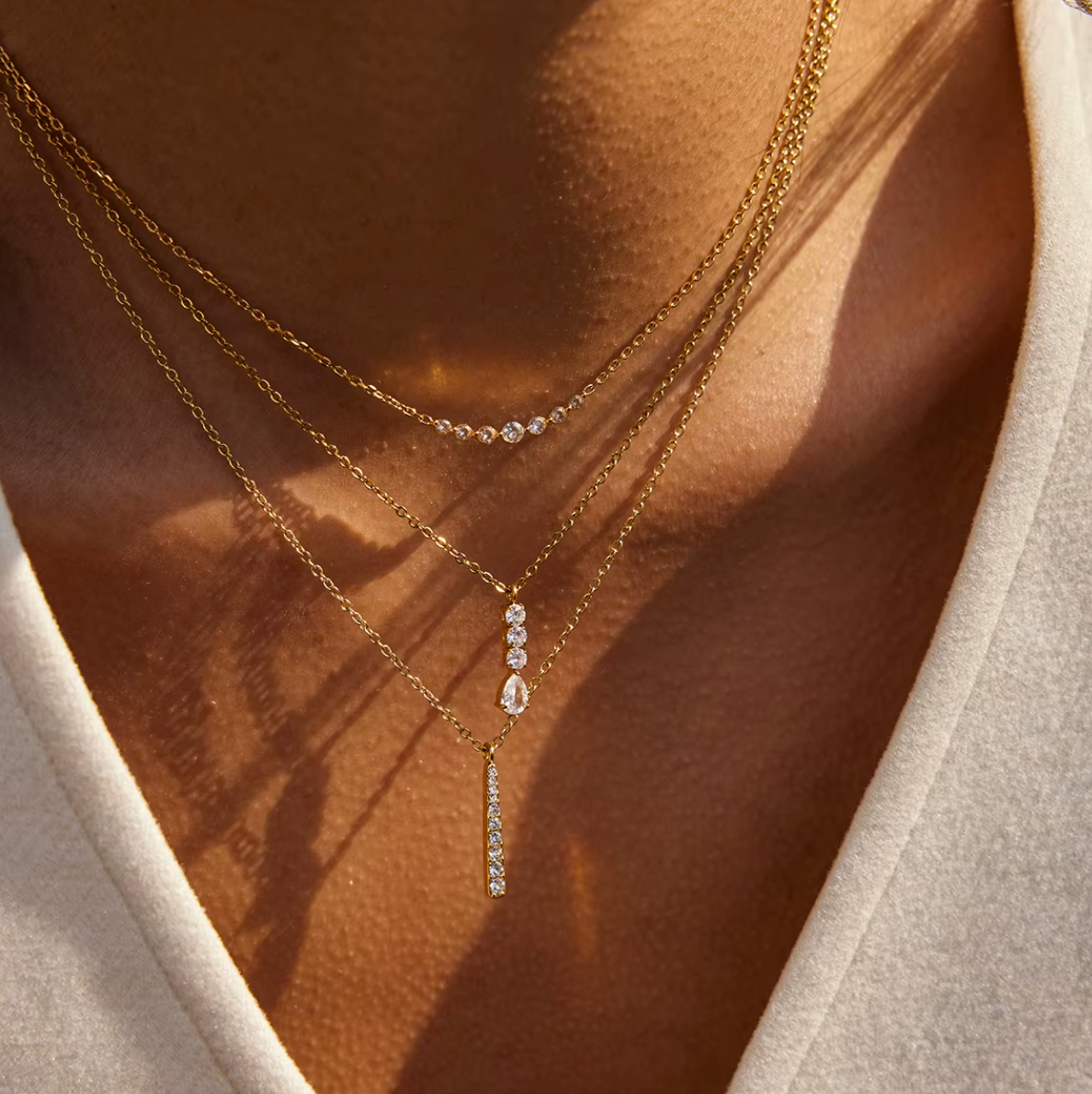 Gold-plated necklace with a fine chain and a slim vertical bar pendant set with clear crystal stones