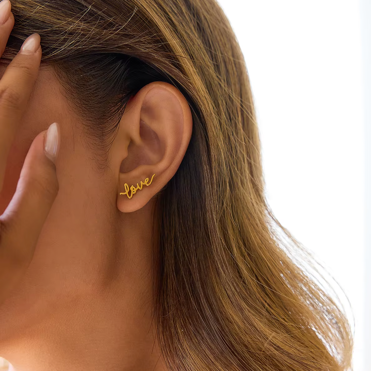 Pair of gold-plated stud earrings spelling “love” in cursive script
