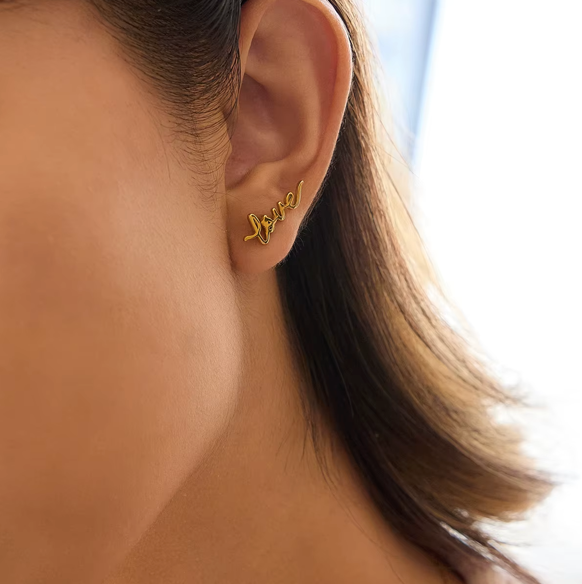 Pair of gold-plated stud earrings spelling “love” in cursive script