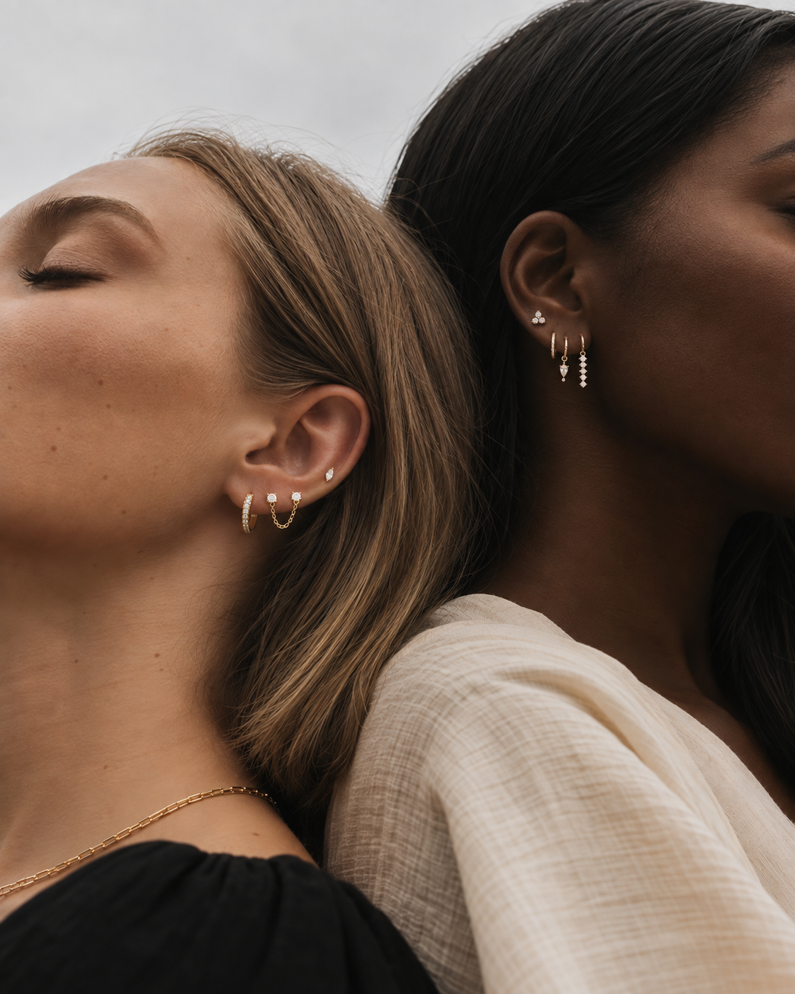 Two models with layered gold ear stacks, styled with several Folie à Trois hoop and stud earrings including huggies and dangles.