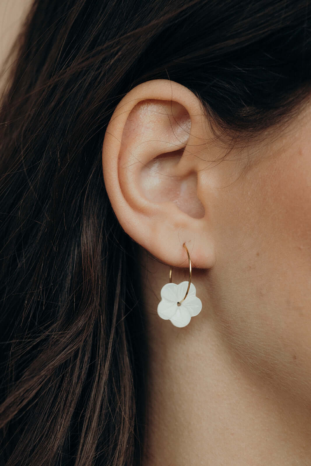 Worn along the ear, After Glow Earrings drop their white flower bead below a delicate gold wire hoop.