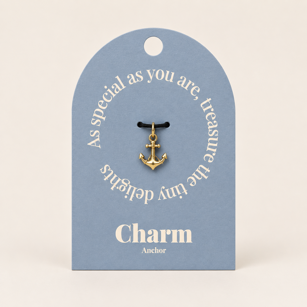 The Anchor CHARM displayed on a dusty blue Charm gift tag, hanging from a black cord against the card's text.