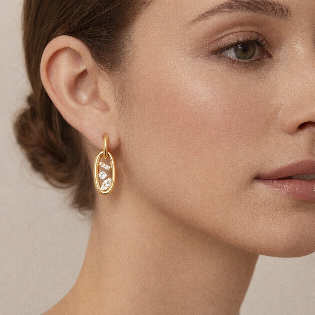 Worn on a model's ear, the Astral EARRINGS oval crystal link dangles delicately below a slim gold hoop.