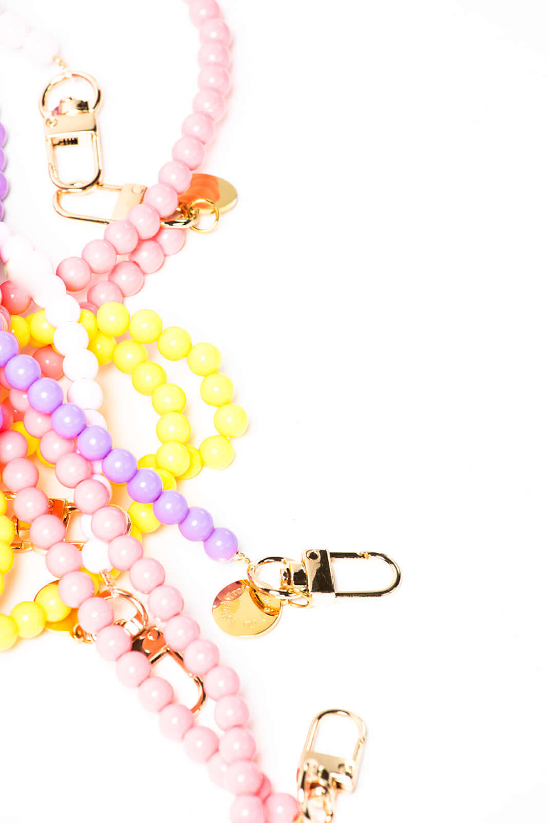 Close-up of tangled pink, yellow, lavender and white beaded Aurora PHONE CORD strands with gold-tone clasps.