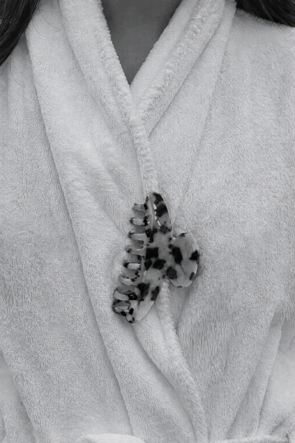 Baby Love HAIR CLIP's black and white dalmatian-print claw clip worn on a white robe collar, shown in black and white.