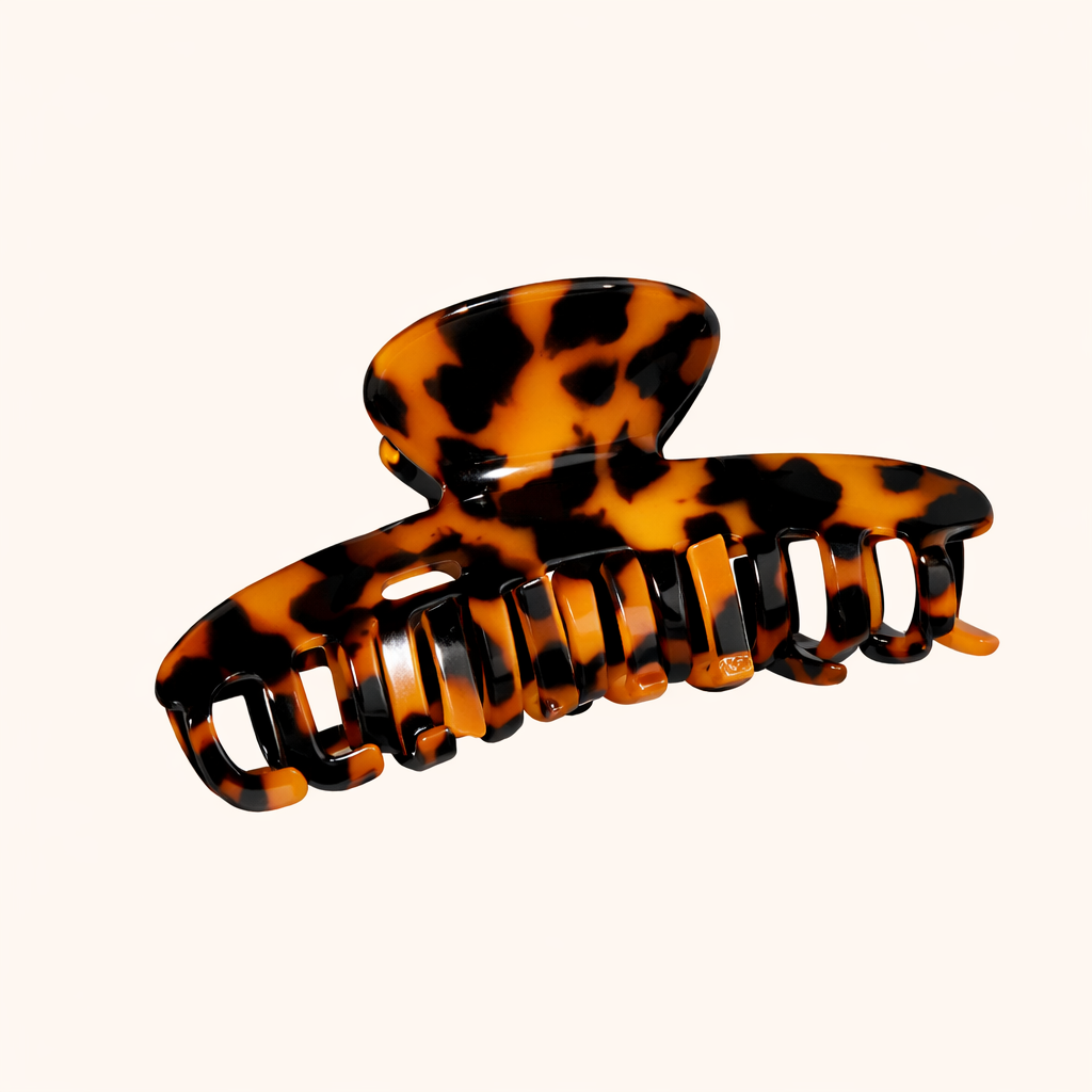 Amber and black tortoiseshell acetate claw clip from the Baby Love HAIR CLIP collection, shown on a cream studio background.