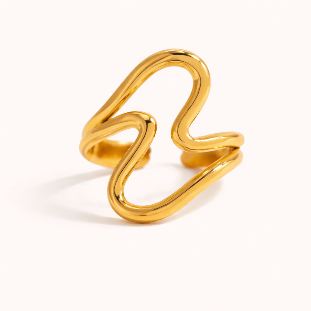 Gold ring formed from wavy interlocking loops in an abstract wave shape, shown on a cream backdrop — Folie à Trois Big Wave RING.