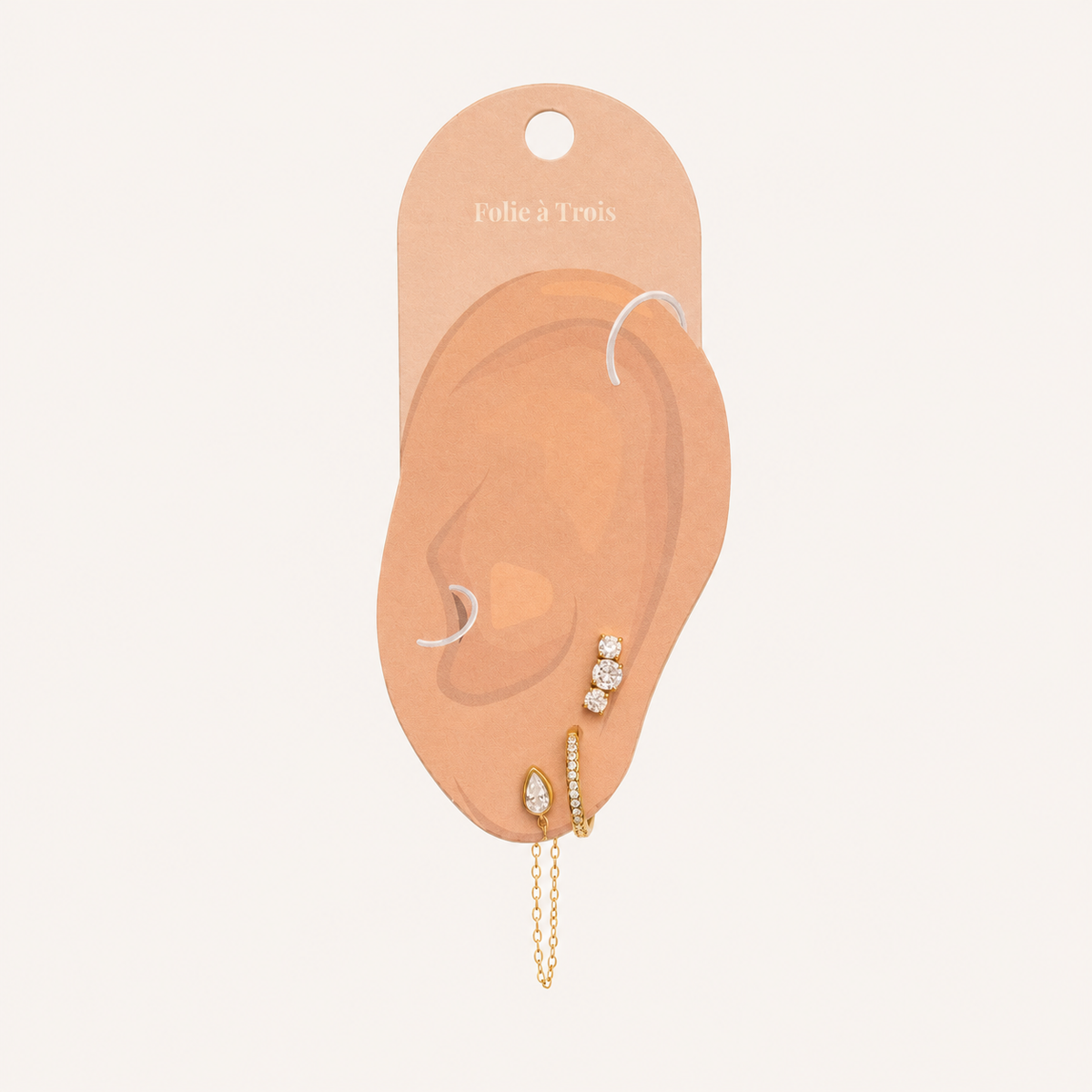 Folie à Trois Bijou SET displayed on a branded ear-shaped card, showing the stud, pavé hoop and chain-drop placement.