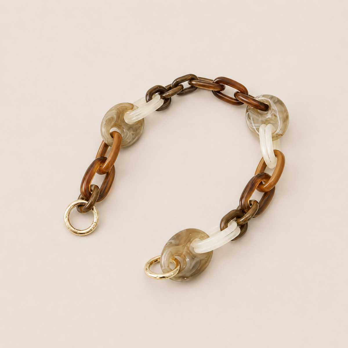 Folie à Trois Bracken short phone chain in brown, tan, white and gray marbled links with gold clasps, laid flat on a cream background.