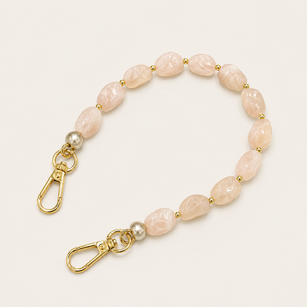 Folie à Trois Briar short wholesale phone chain in blush marbled nugget beads with silver pearl accents and gold clasps, coiled on a cream background.