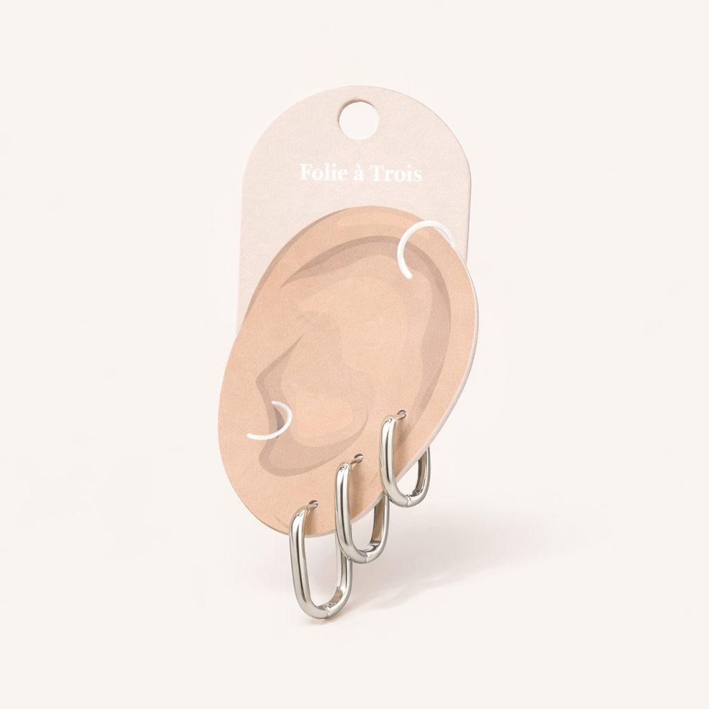 Illustrated Folie a Trois earring card showing the silver-tone Bruna Set hoops on an ear-shaped display.