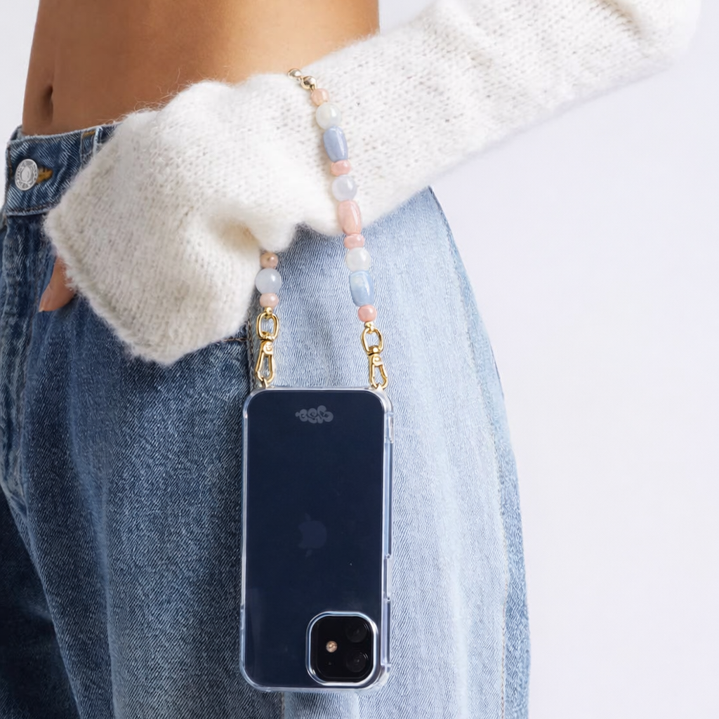 Model holds her phone by the blue and pink beaded Celia strap, phone in a navy case at the hip.