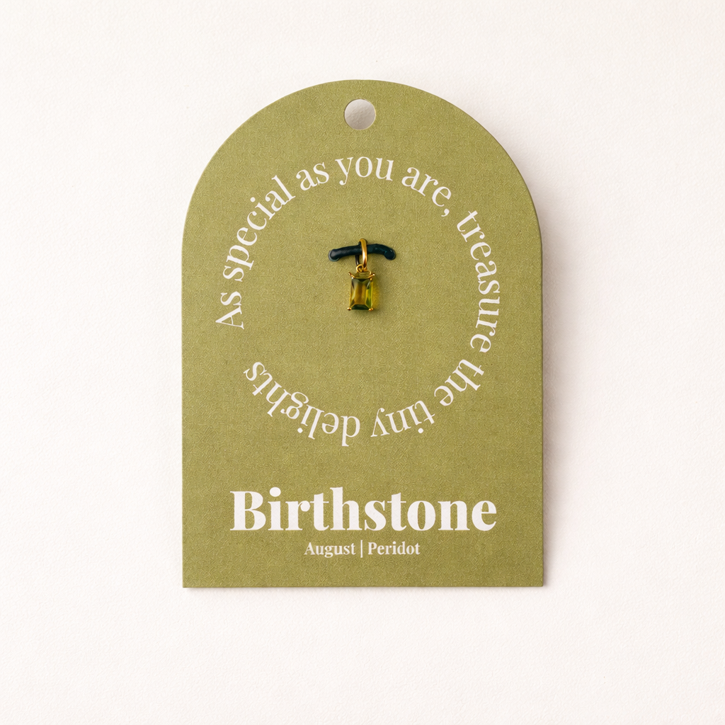 The Classic Drop Birthstone Charm in olive peridot hangs from a black cord on an olive gift card reading Birthstone, August, Peridot.
