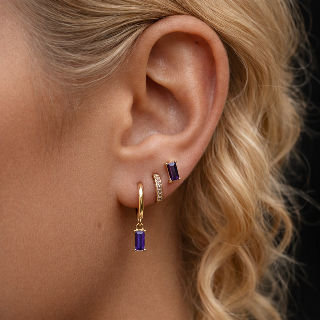 A model wears the Classic Drop SET in amethyst purple, layering a baguette stud, dangle hoop, and pavé hoop along the ear.