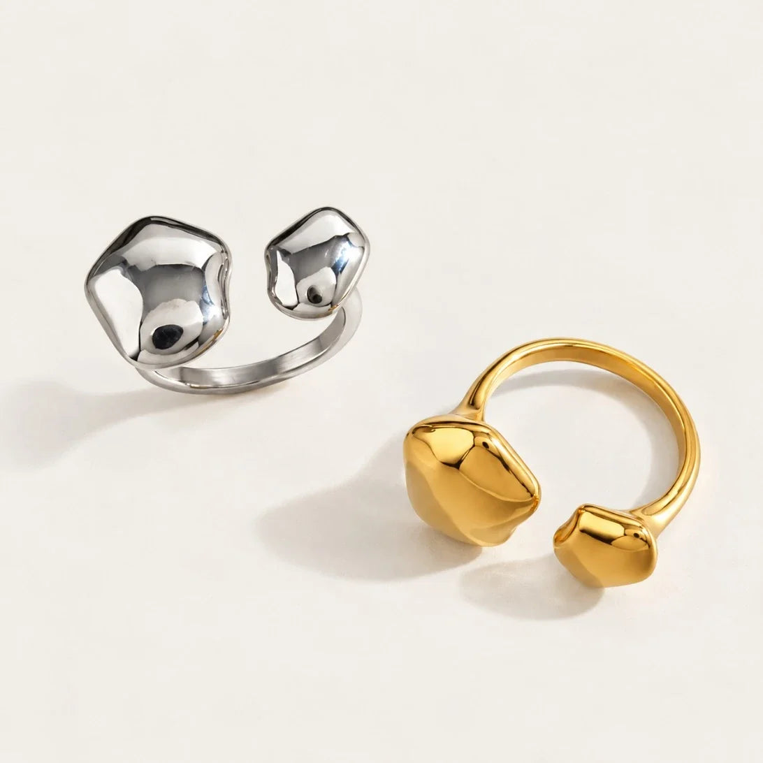 Two Cloud RINGS in silver-tone and gold with smooth, organic pebble-shaped ends on a cream background — Folie à Trois