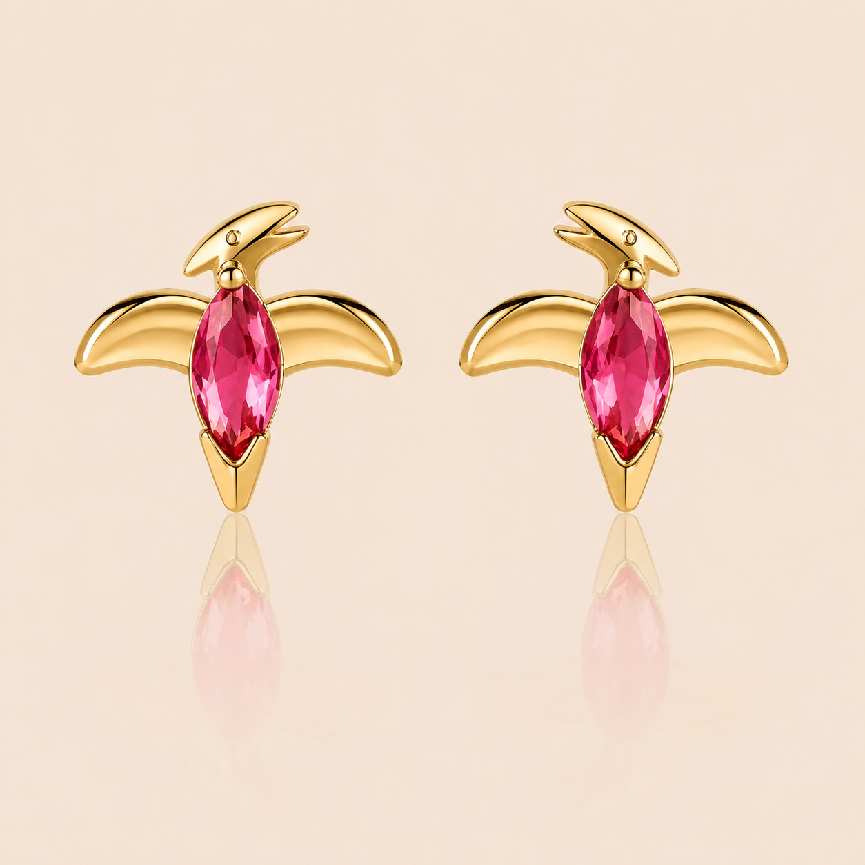 Gold pterodactyl-shaped stud earrings from the Colorful Dino EARRINGS with a pink marquise cubic zirconia body and outstretched wings.