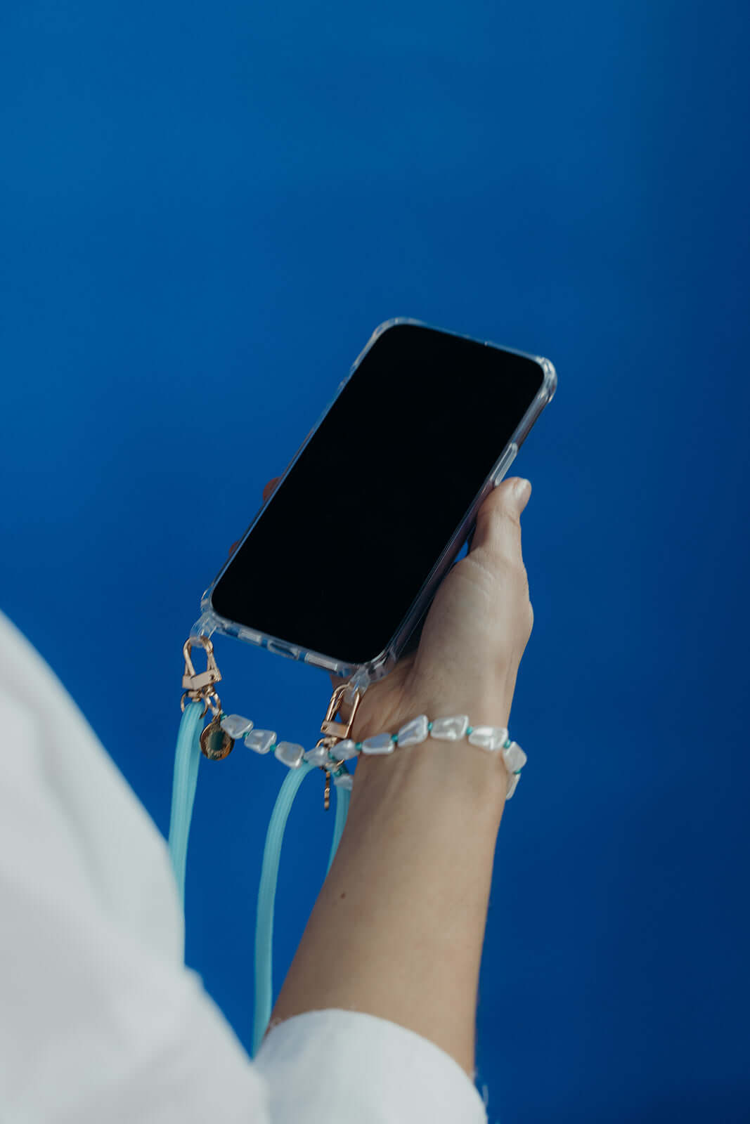 Light blue Colorful PHONE CORD paired with a beaded strap, model holding her phone against a blue background.