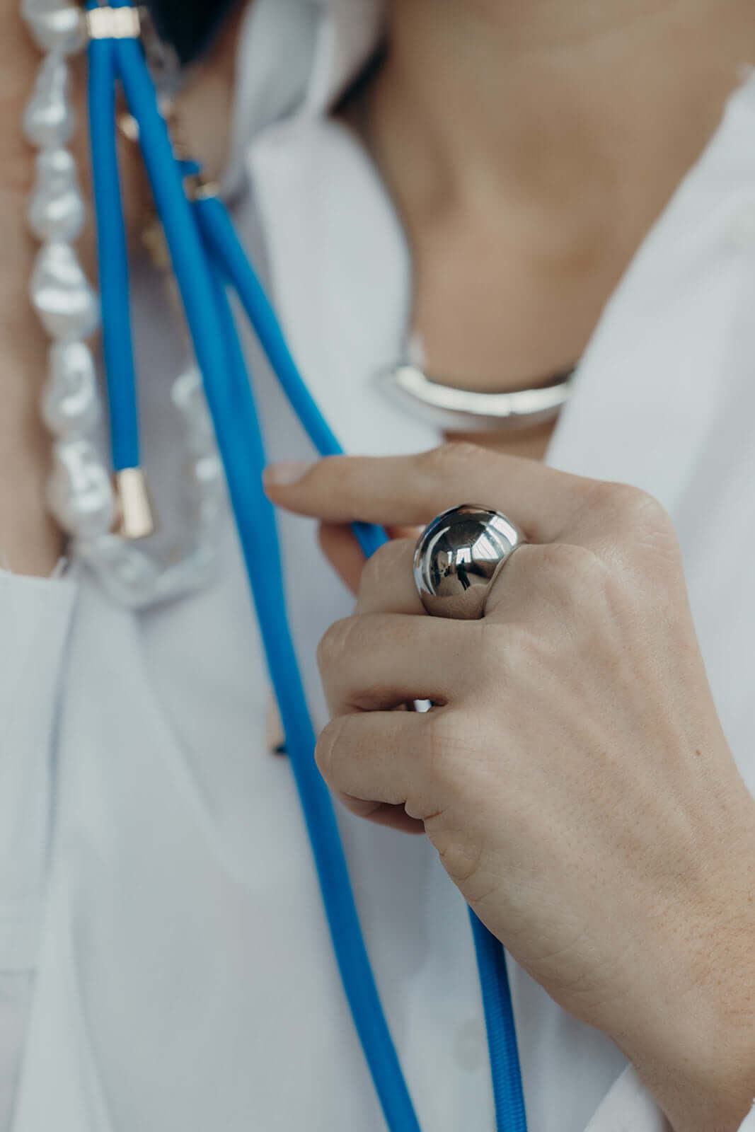 Close-up of a light blue Colorful PHONE CORD and pearl bead bracelet clasps on a model's hand.