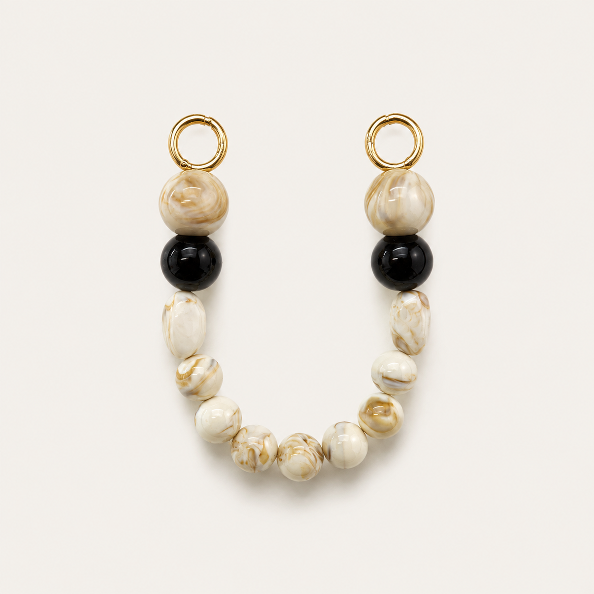 Cream marble bead phone chain with black accents and gold hoop clasps on a cream background — Folie à Trois Delphine short phone chain