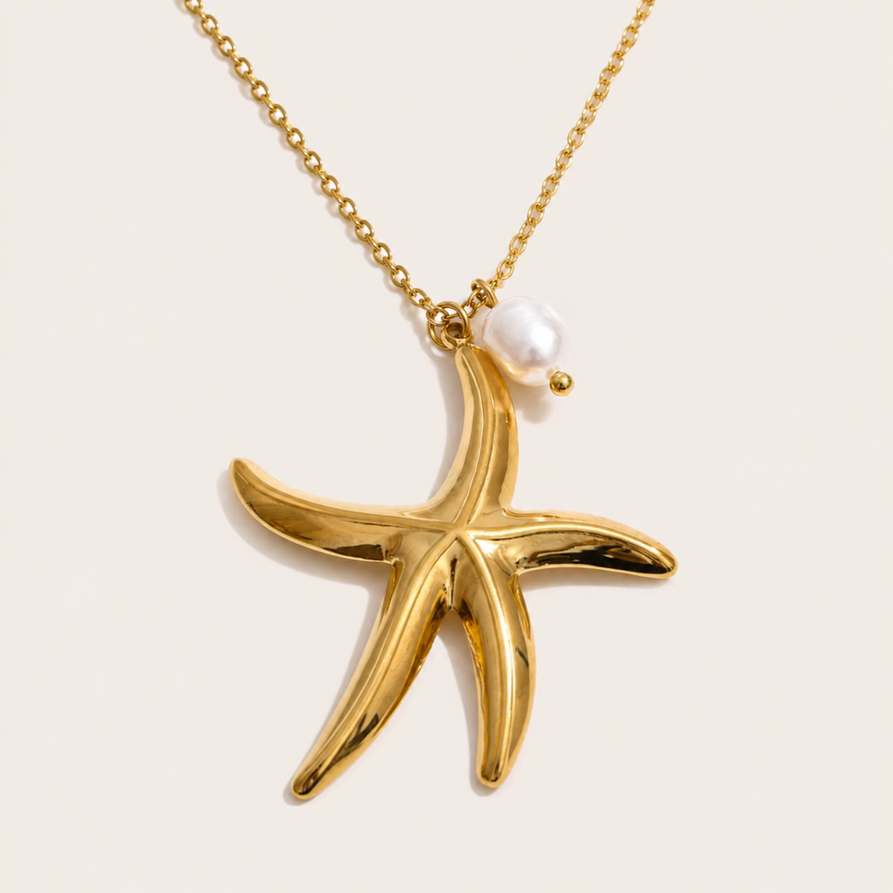 Gold chain necklace with a polished starfish pendant and pearl accent from the Dolce Mare NECKLACE design, laid flat.
