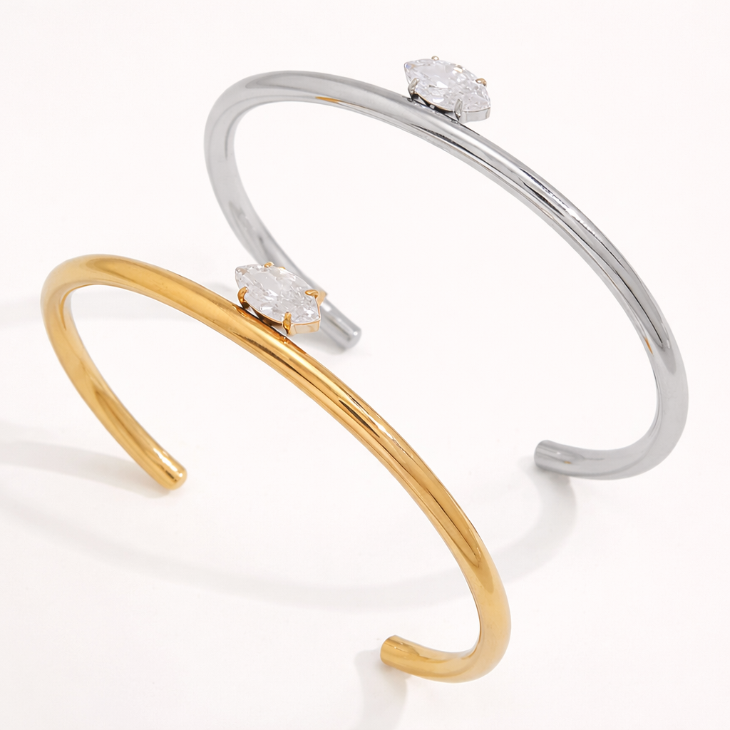 Electric Frost BRACELET pair in gold and silver, open cuffs each set with a single marquise crystal, shown together.
