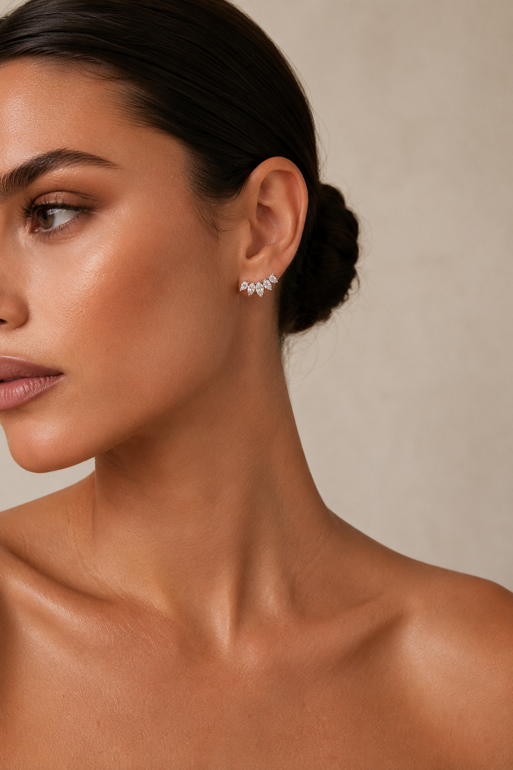 Model with a sleek low bun wears the gold Facet EARRINGS, marquise-cut zirconia climber studs catching light at the earlobe.