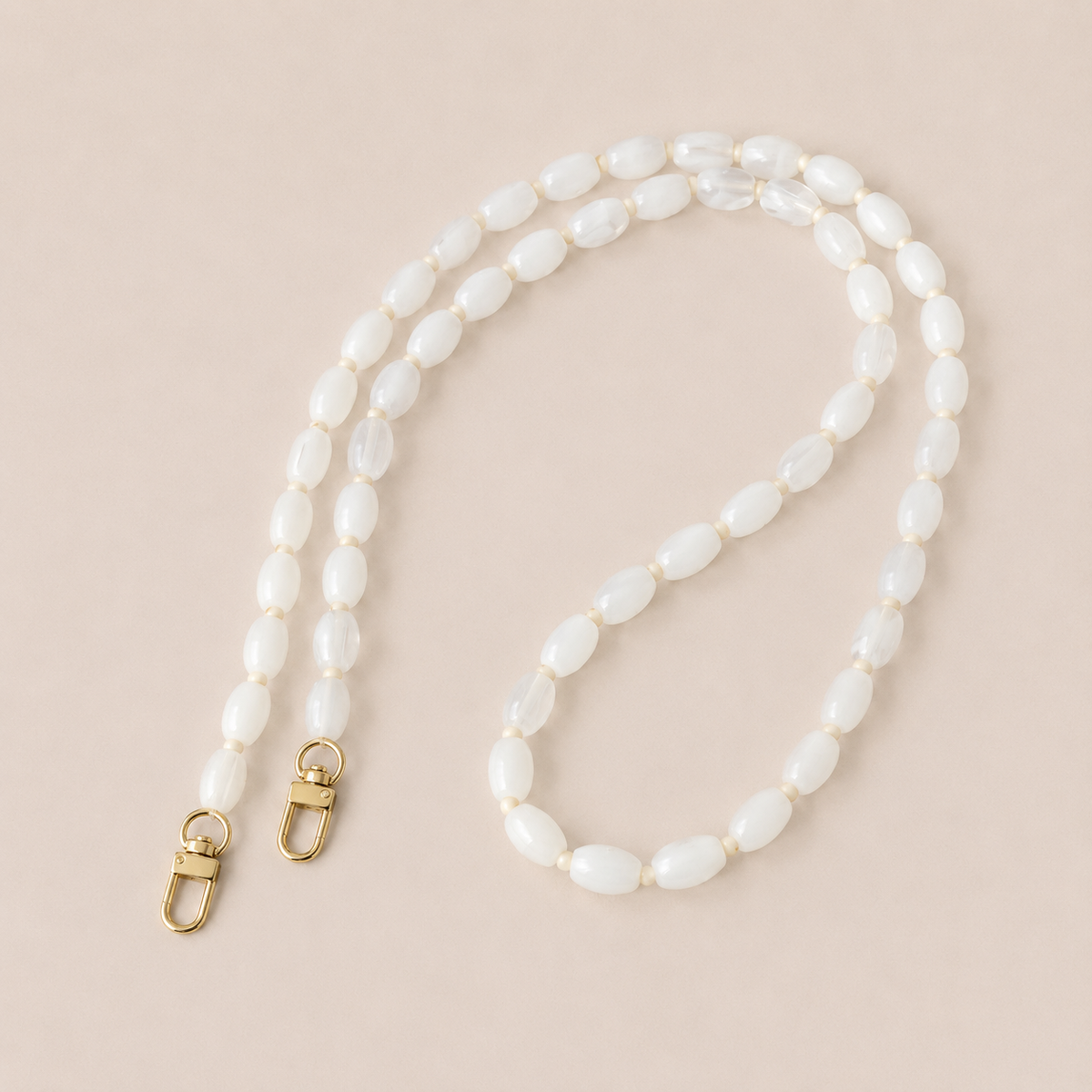 Folie à Trois Fennel long phone chain in white oval beads with cream spacers and gold clasps, laid flat on a cream background.