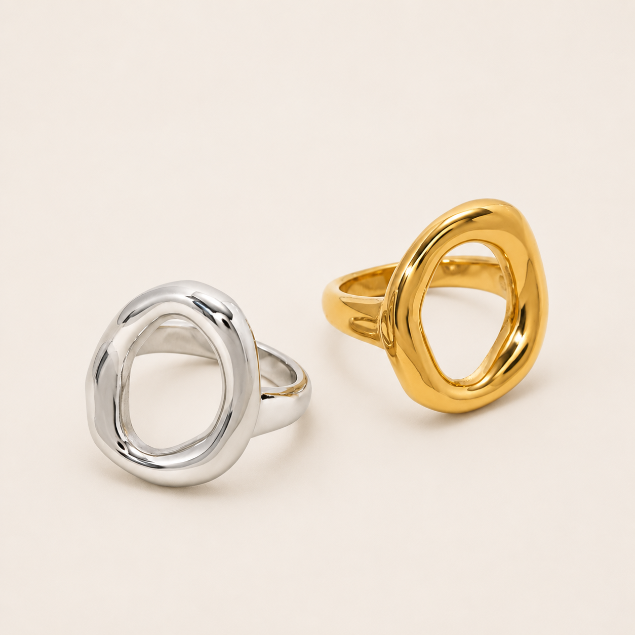 Silver and gold Formentera RING side by side, each an open organic asymmetric loop with a chunky polished band, on a cream backdrop.