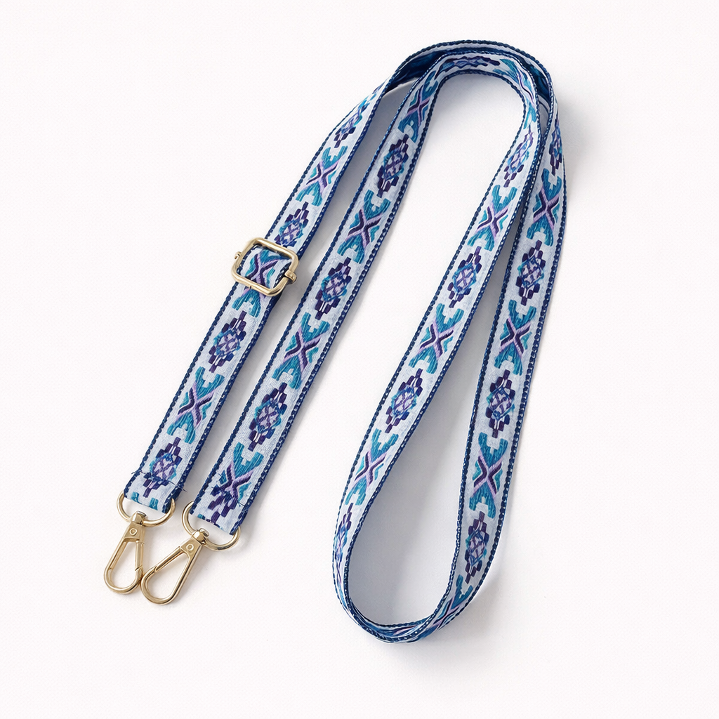 Woven Getaway long phone strap in blue and purple Aztec pattern, coiled flat with gold clasps.