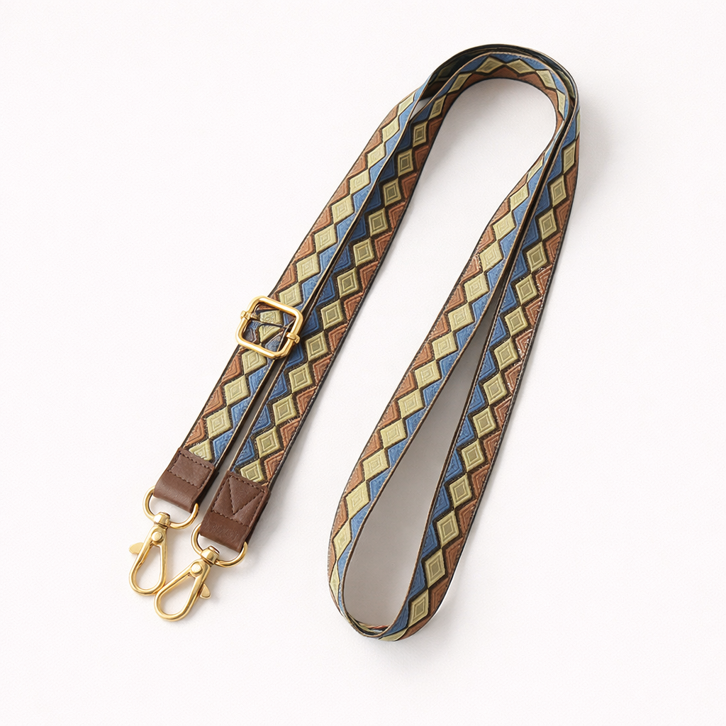 Woven Getaway long phone strap in tan, blue, and brown diamond pattern, coiled flat with gold clasps.