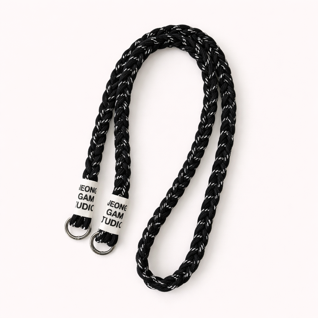 Black braided cord Havana long phone strap with fleck detailing, coiled with silver ring hardware.