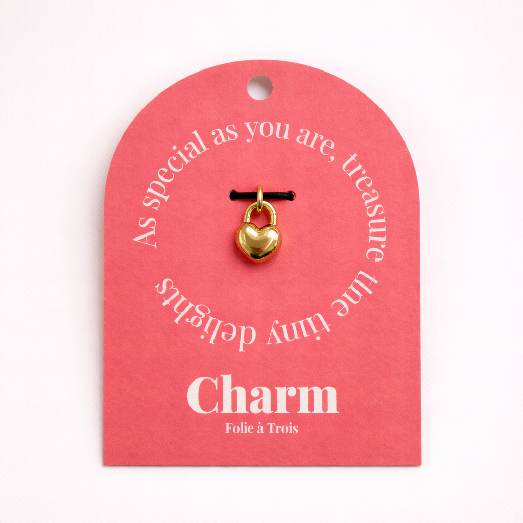 The Heart Locket CHARM displayed on a coral pink Charm gift tag, hanging from a black cord against the card's text.