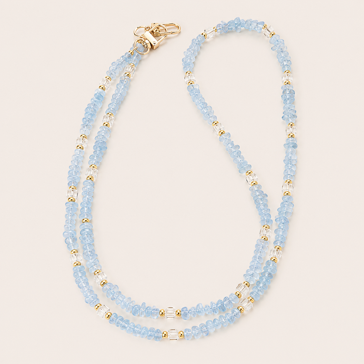 Double-strand light blue and faceted clear bead phone chain with gold accents on cream — Folie à Trois Hollis long phone chain
