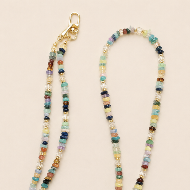 Close-up of a multicolour rondelle bead phone chain with gold clasps on cream — Folie à Trois Hollis long phone chain