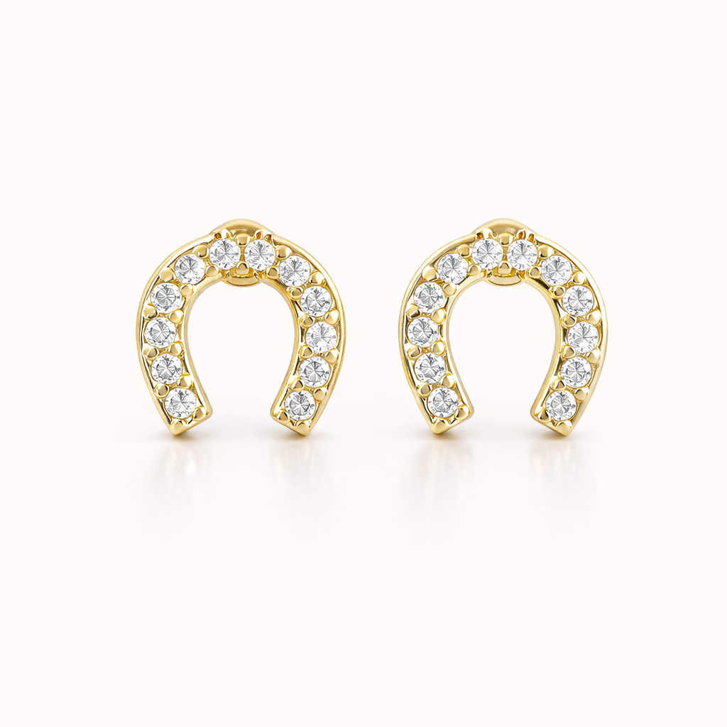 The Horseshoe EARRINGS are gold studs shaped like horseshoes, fully lined with sparkling round crystals.