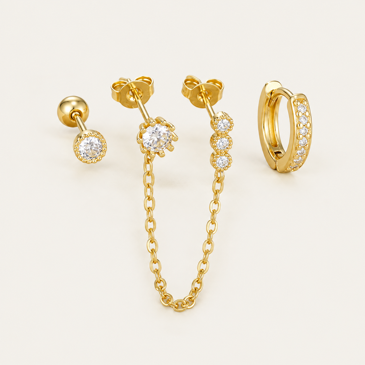 Four gold Folie à Trois Ines SET pieces: a bezel stud, a bezel stud linked by chain to three small drops, and a pavé huggie hoop.