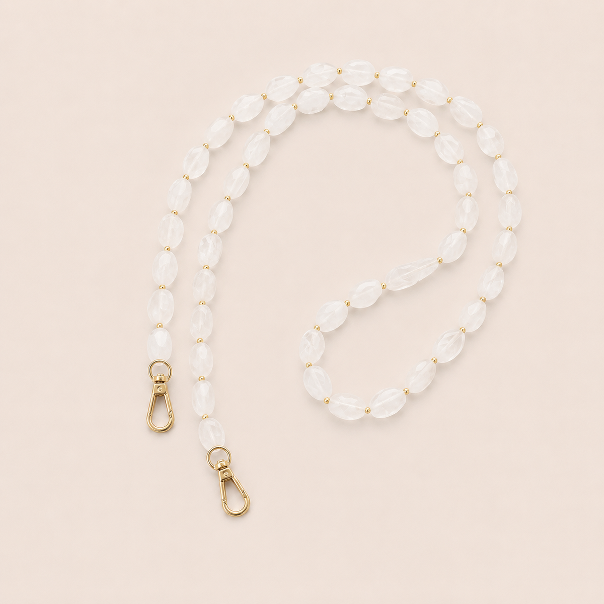 Folie à Trois Isolde long phone chain in frosted white opal-effect beads with gold accent beads and gold clasps, styled flat on a cream background.