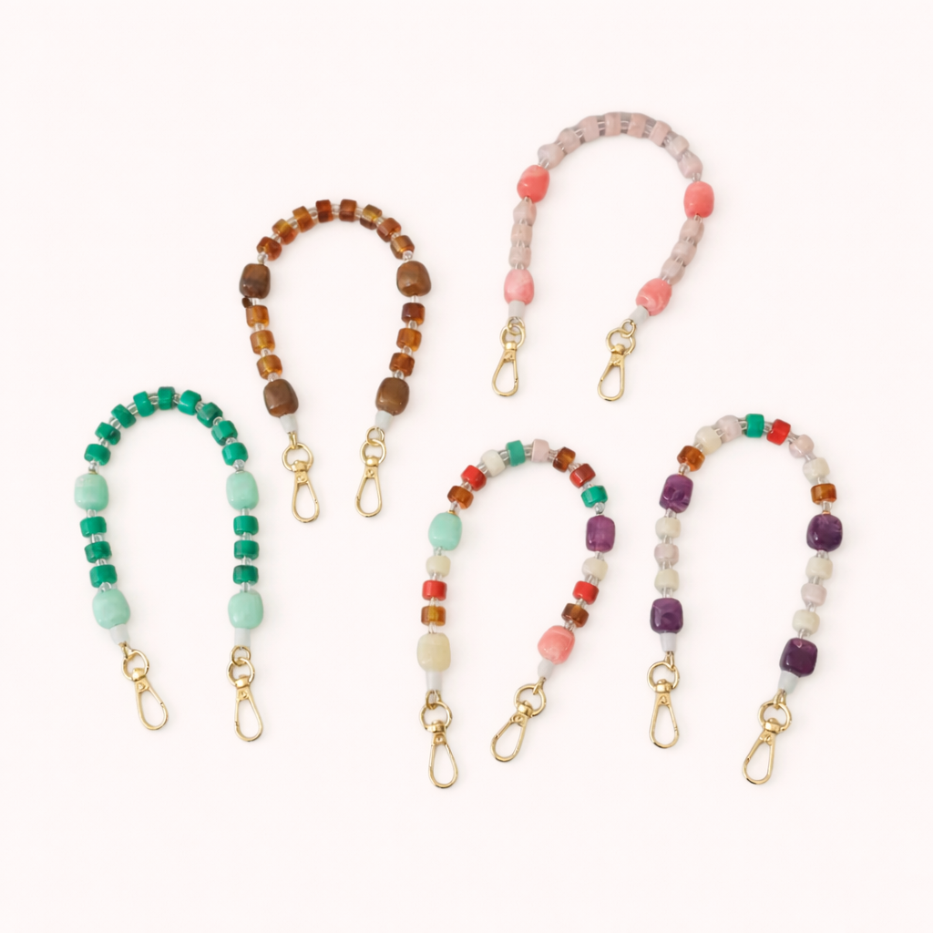 Five Jaqueline SHORT PHONE STRAP styles in mint green, brown, dusty pink, and mixed pastel beads with gold-tone clasps.