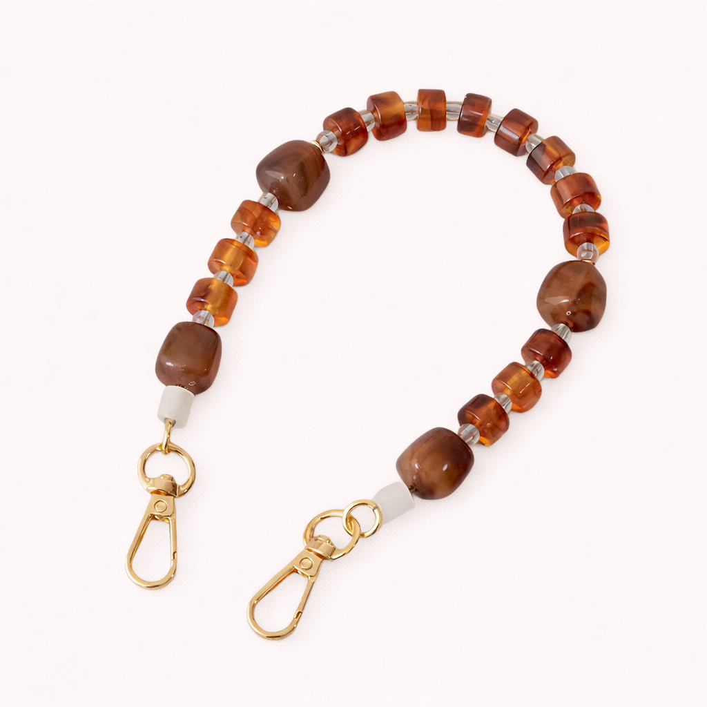 The Jaqueline SHORT PHONE STRAP in warm amber and brown marbled beads with clear glass spacers and gold-tone clasps.