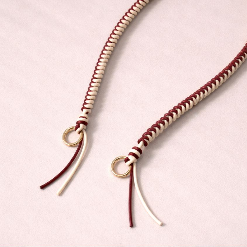 Burgundy and cream two-tone braided Layover strap, close-up of the knotted gold ring and fringe end.
