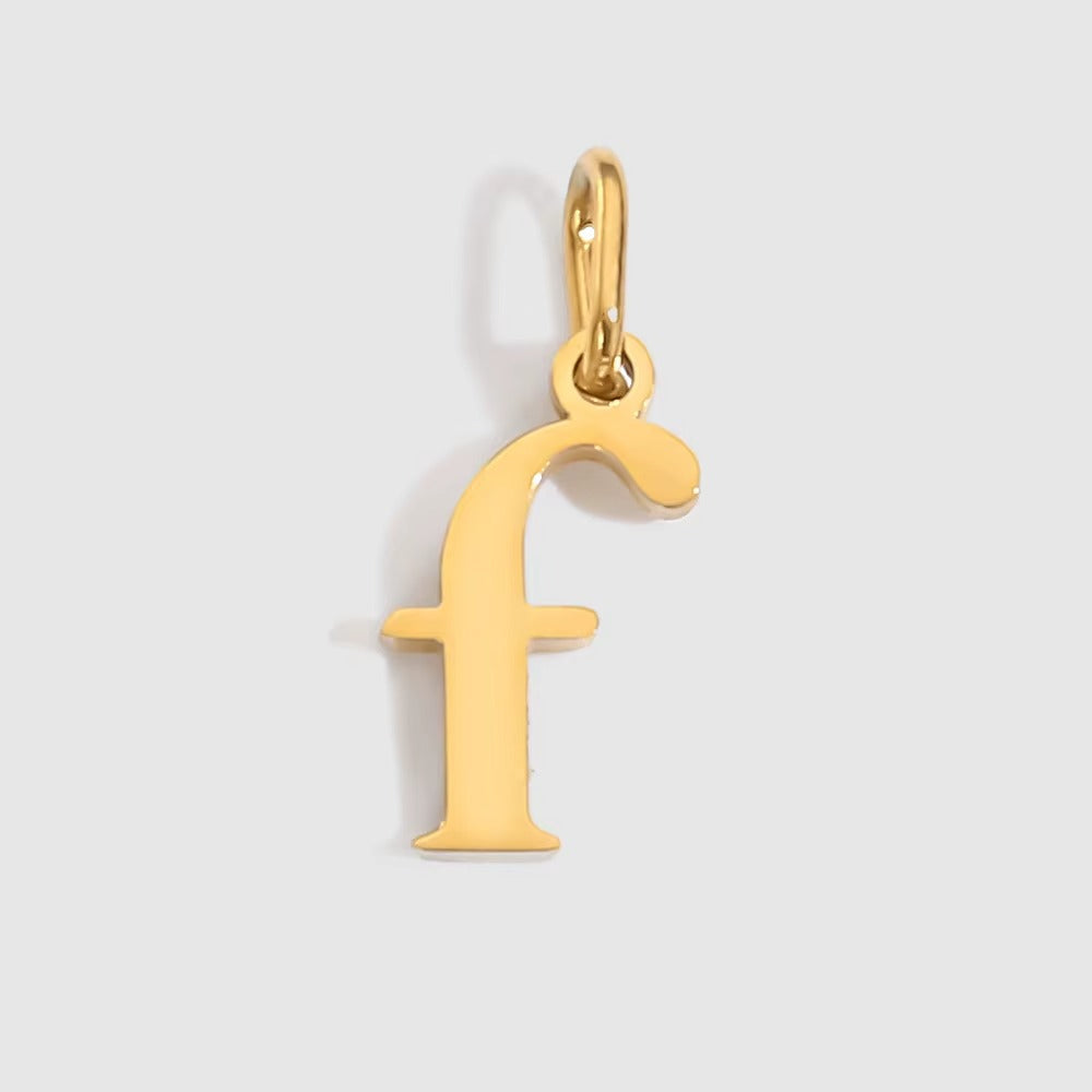 The Letter CHARM in lowercase f, a polished gold pendant in a serif f shape, shown in close-up on a light grey background.