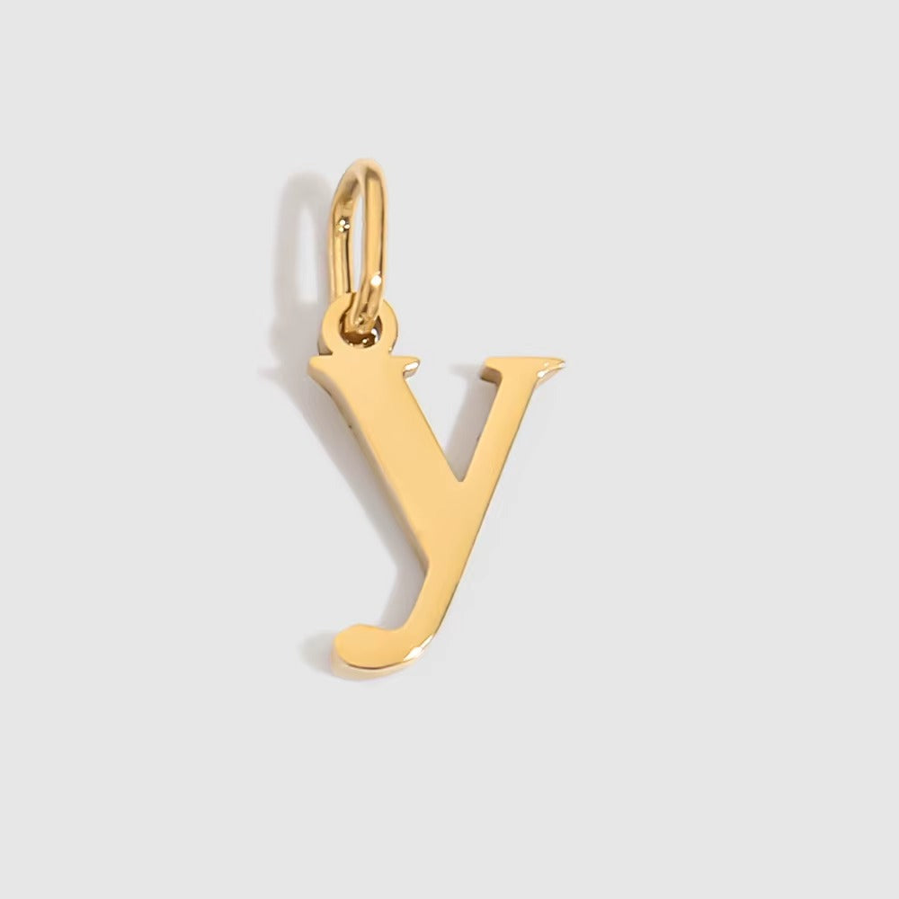 The Letter CHARM in lowercase y, a polished gold pendant in a serif y shape, shown in close-up on a light grey background.