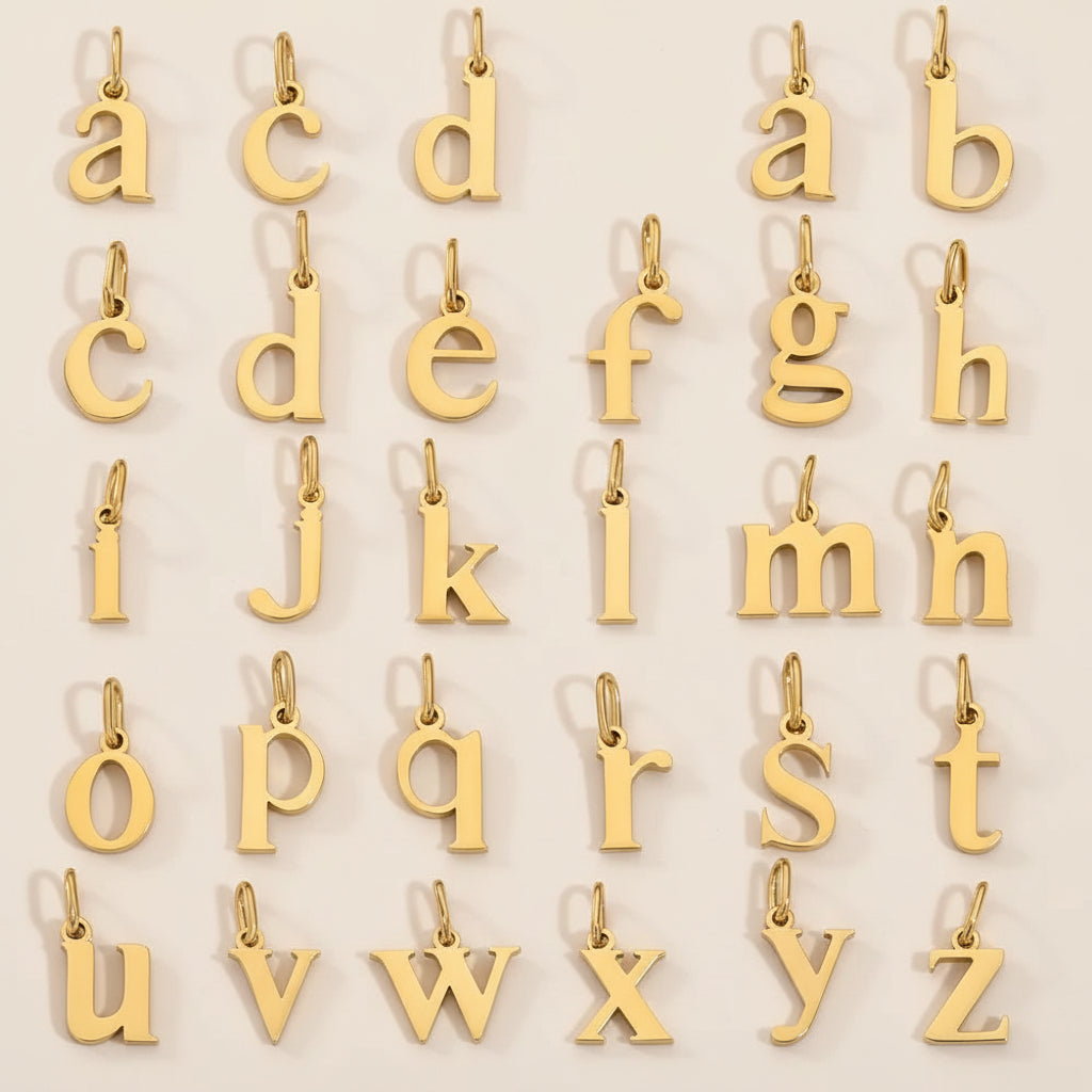 The Letter CHARM full alphabet, all twenty-six polished gold lowercase letters a to z arranged in rows on a cream background.