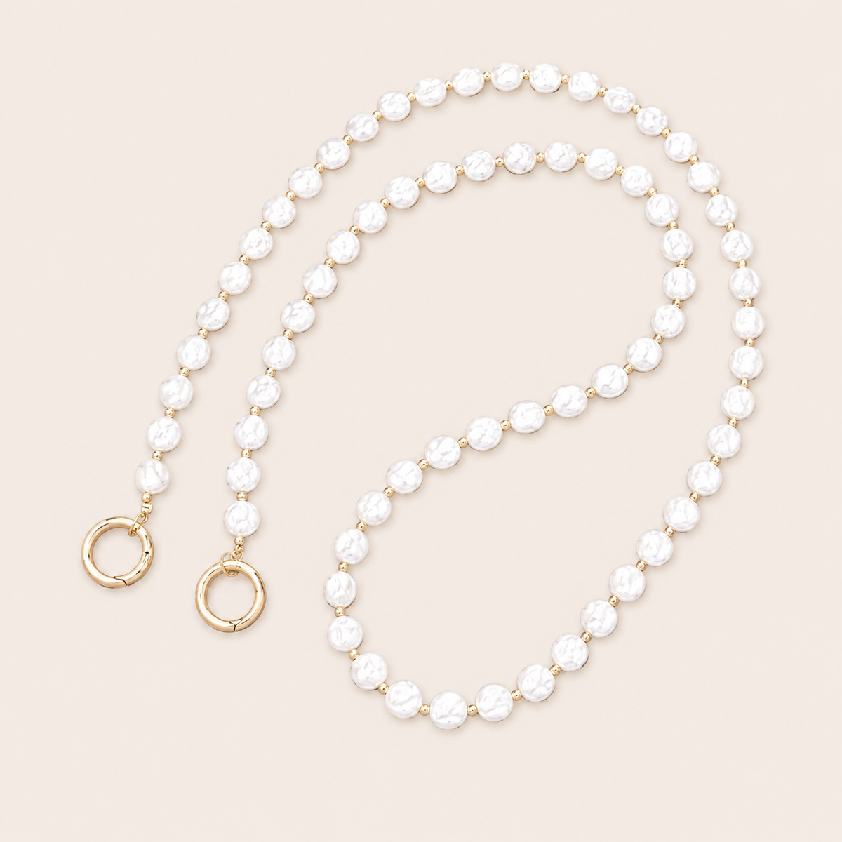 Folie à Trois Linden Pearl phone chain in textured white faux pearls with gold spacer beads and gold ring clasps, coiled on a cream background.