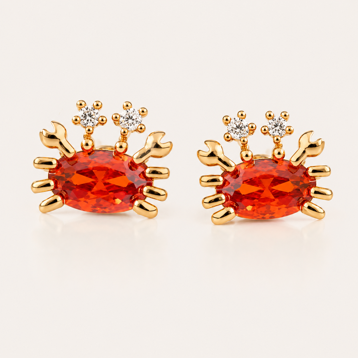 Gold Little Crab EARRINGS stud with an orange oval cubic zirconia body, gold claws and legs, and two small white round accent stones.